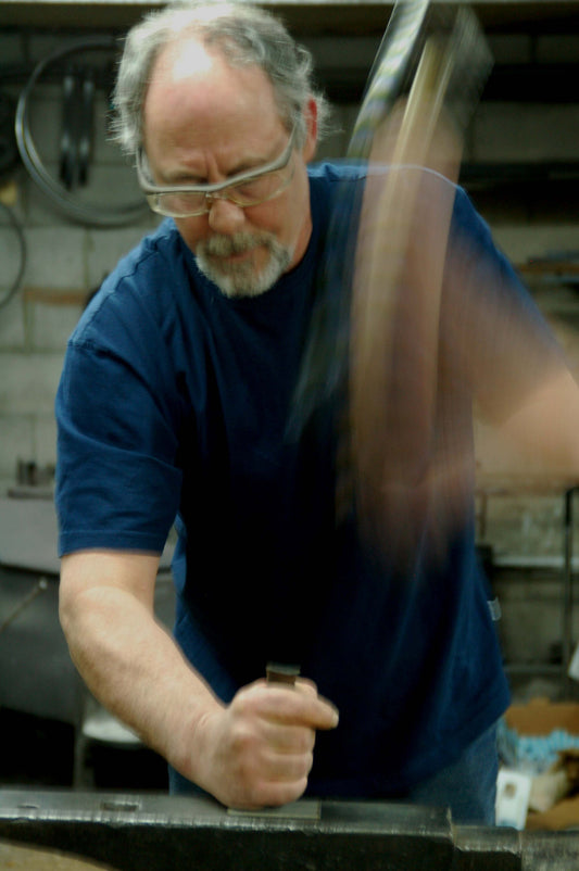 Robert Aucoin, hand punching his signature onto one of his hand-forged belt buckles.
